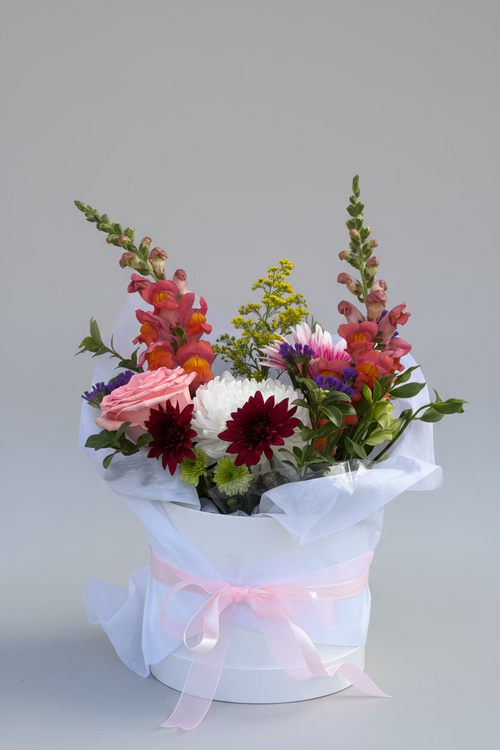 Bouquet of flowers wrapped in white paper with a pink ribbon on a purple background